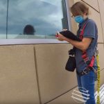 Restoration Consultant Erika Green makes notes on an iPad as she examines a building facade from a swing stage