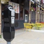 A parking meter for a curb space with sidewalk dining in the background