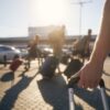 People walk through the parking lot at an airport with their rolling luggage