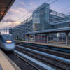 A train passes through the Stamford train station with the Stamford Transportation Center parking structure behind it
